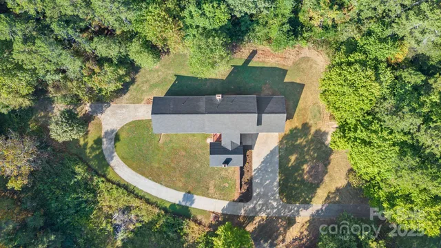 an aerial view of a house with swimming pool and large trees