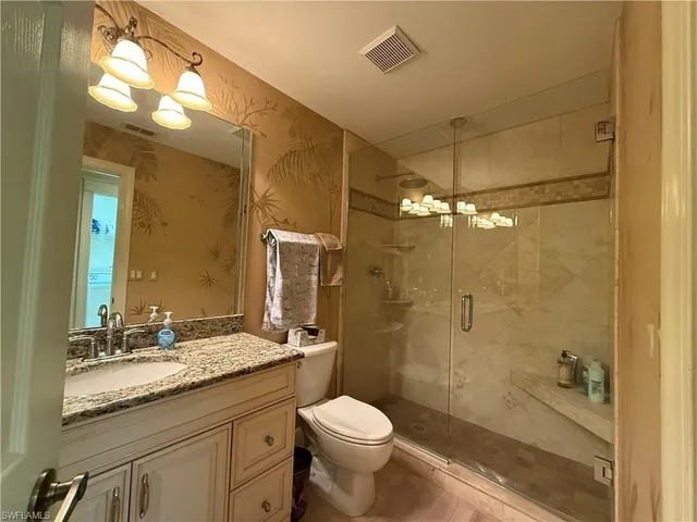 a bathroom with a granite countertop sink toilet and shower