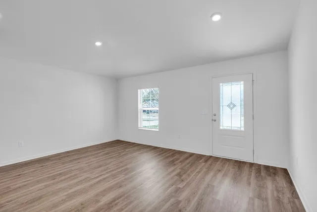 an empty room with wooden floor and windows