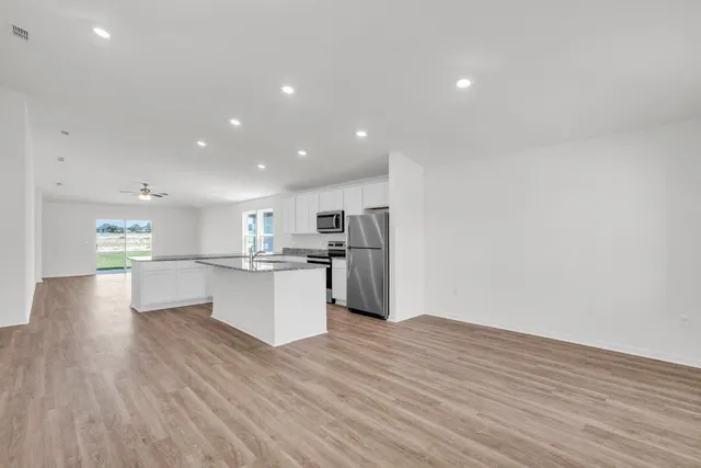 a view of kitchen with kitchen island wooden floors and stainless steel appliances