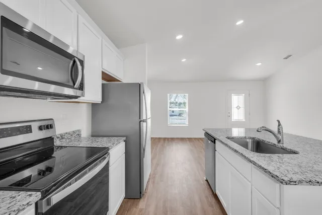 a kitchen with stainless steel appliances granite countertop a sink stove and refrigerator