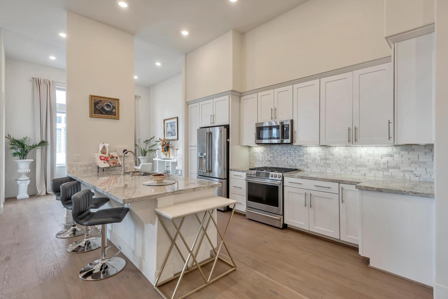 1038 Foster Square Lane, Unit 403 Foster City, CA 94404 - Photo 5 of 28 a kitchen with stainless steel appliances granite countertop a stove top oven a sink dishwasher a refrigerator and white cabinets with wooden floor