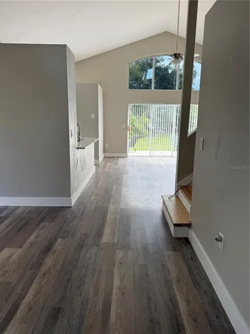 a view of empty room with wooden floor and fan