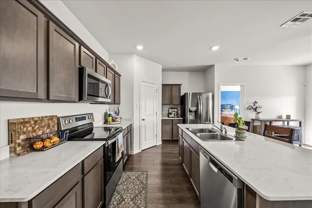 a kitchen with stainless steel appliances granite countertop a sink a stove and a refrigerator