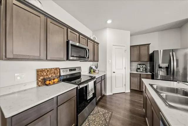 a kitchen with stainless steel appliances granite countertop a sink stove microwave and refrigerator