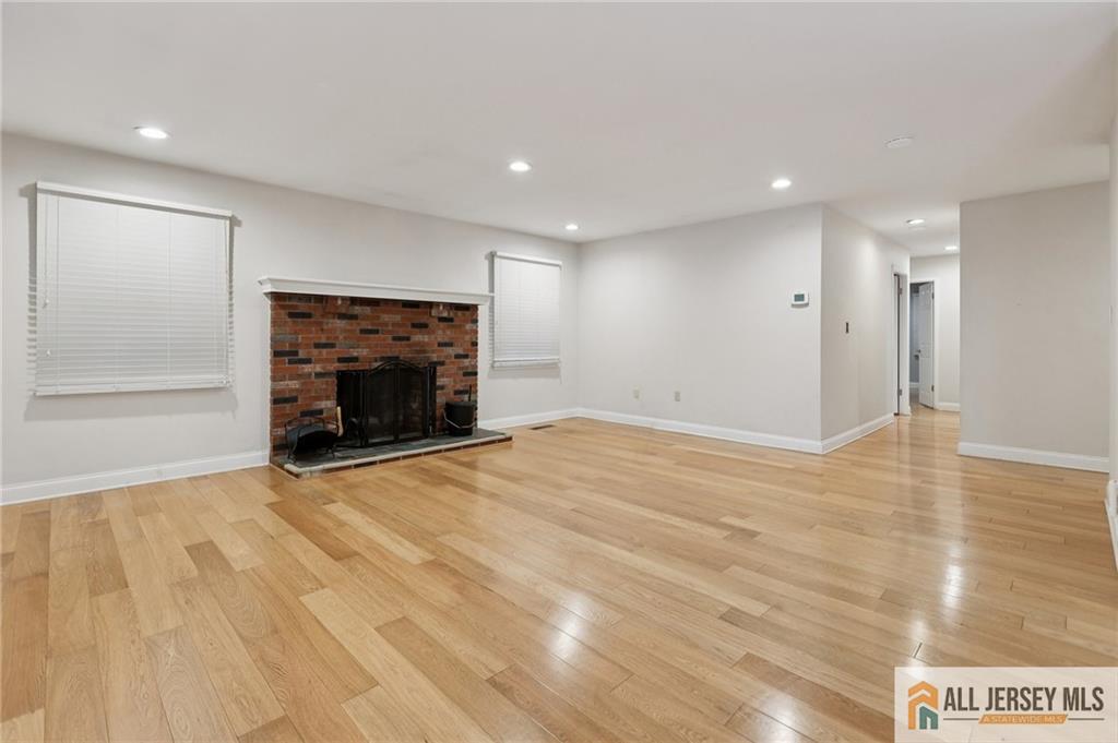 1 Landry Road Somerset, NJ 08873 - Photo 6 of 17 an empty room with wooden floor fireplace and windows