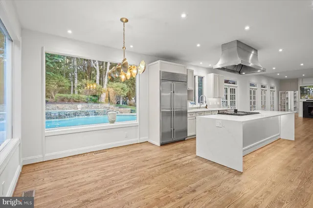 a large kitchen with kitchen island a large counter top and stainless steel appliances