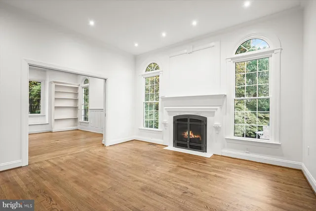 an empty room with windows and fireplace