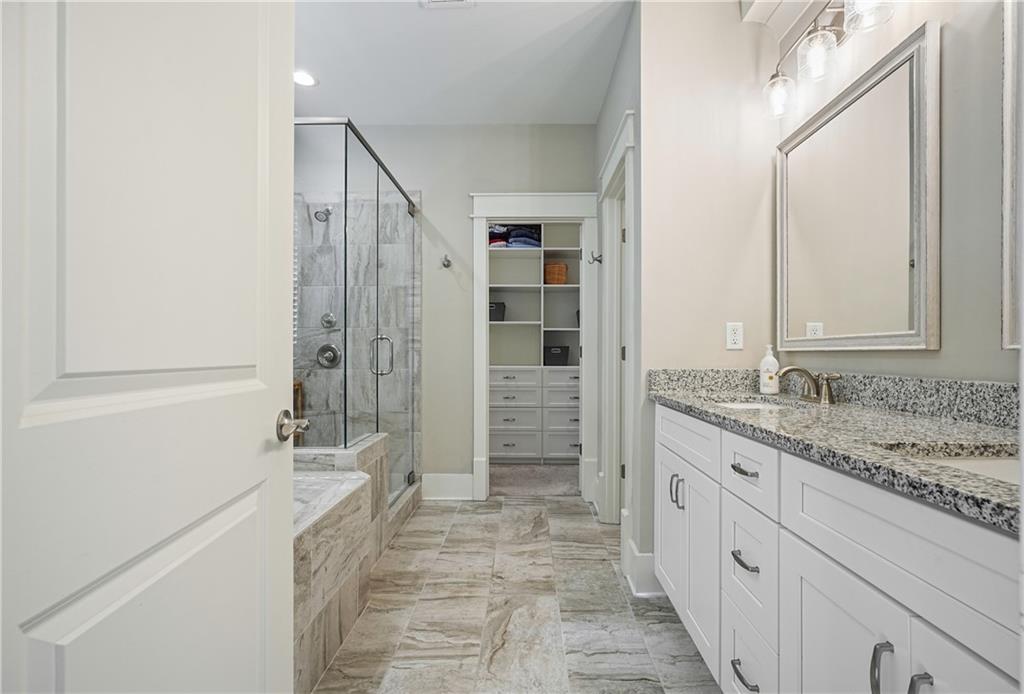 6243 Allen Ivey Road Mableton, GA 30126 - Photo 22 of 46 a bathroom with a granite countertop sink a mirror a shower and a bathtub