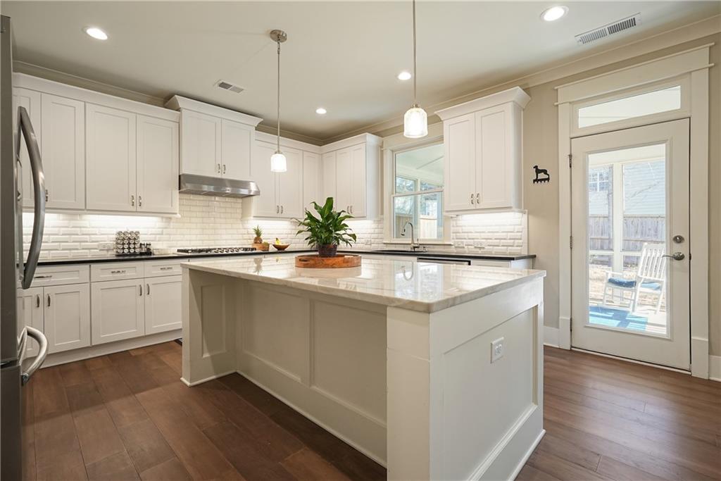 6243 Allen Ivey Road Mableton, GA 30126 - Photo 8 of 46 a kitchen with stainless steel appliances granite countertop a sink a stove a refrigerator and island with wooden floor