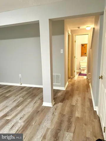 a view of a hallway with wooden floor and a bathroom