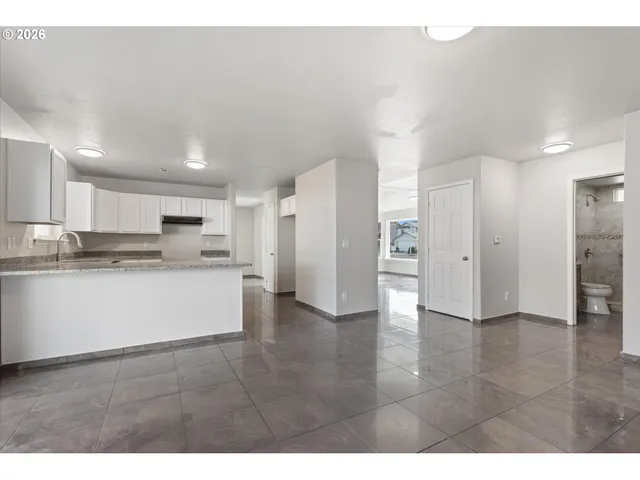 a view of a kitchen with refrigerator and white cabinets
