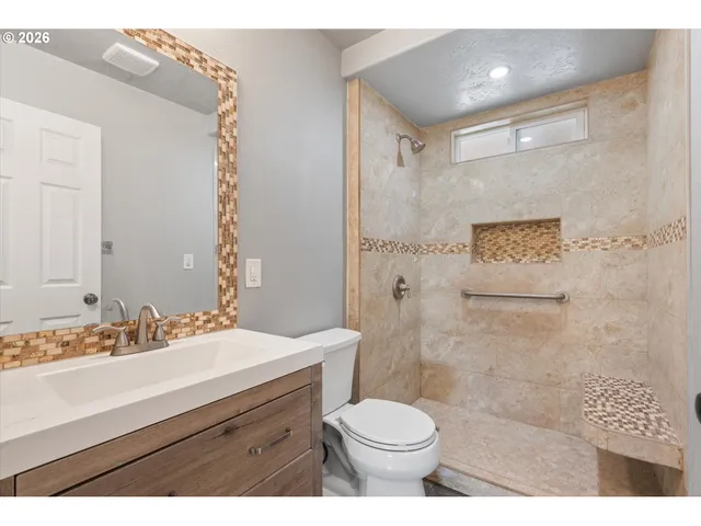 a bathroom with a sink a toilet a shower and a mirror