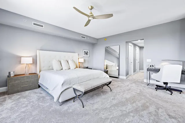 a bedroom with a bed large mirror and a lamp