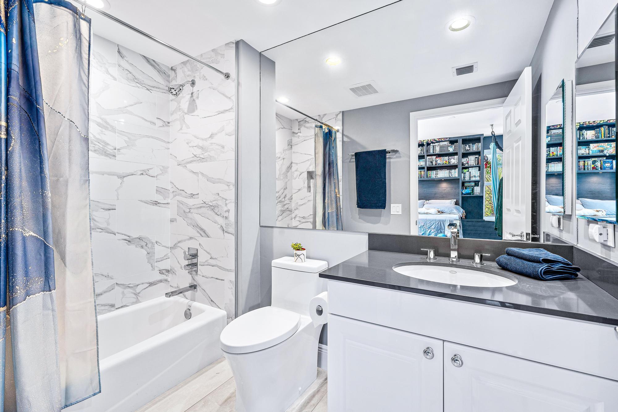 500 Highway 1, Unit 201 Jupiter, FL 33477 - Photo 26 of 38 a bathroom with a granite countertop sink a toilet a mirror a bathtub and shower