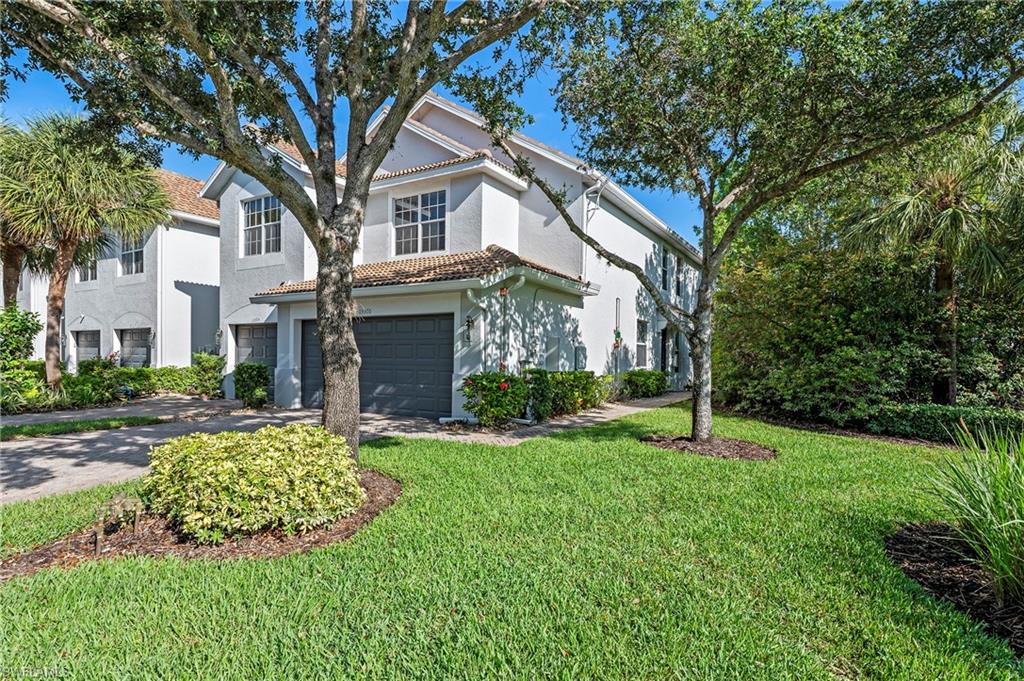 a front view of a house with a garden and trees