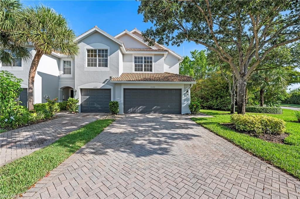 15570 Marcello Circle, Unit 149 Naples, FL 34110 - Photo 2 of 31 a front view of a house with a garden and trees