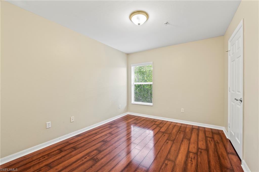 15570 Marcello Circle, Unit 149 Naples, FL 34110 - Photo 24 of 31 an empty room with wooden floor and windows