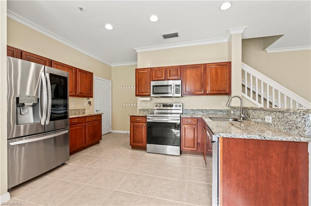 15570 Marcello Circle, Unit 149 Naples, FL 34110 - Photo 8 of 31 a large kitchen with stainless steel appliances granite countertop a stove a sink dishwasher a refrigerator and a microwave oven