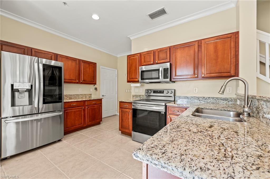 15570 Marcello Circle, Unit 149 Naples, FL 34110 - Photo 9 of 31 a kitchen with stainless steel appliances granite countertop a refrigerator stove and sink