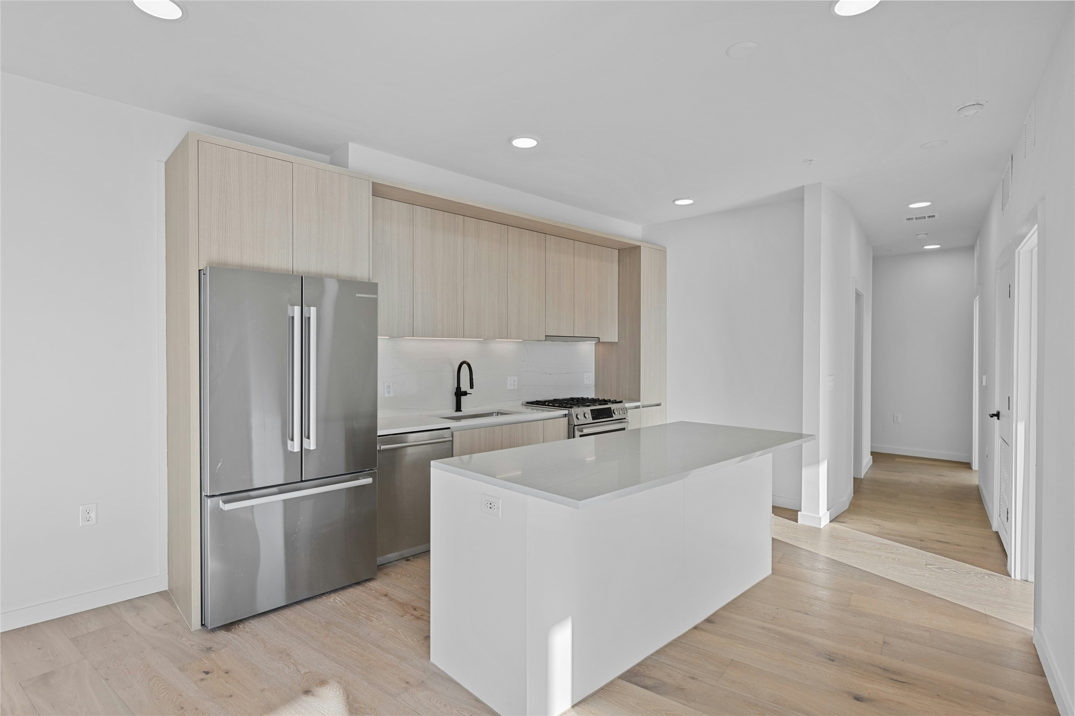 2209 South 1st Street, Unit 321 Austin, TX 78704 - Photo 4 of 40 Kitchen with stainless steel appliances, modern cabinets, light wood-style flooring, recessed lighting, and a kitchen island