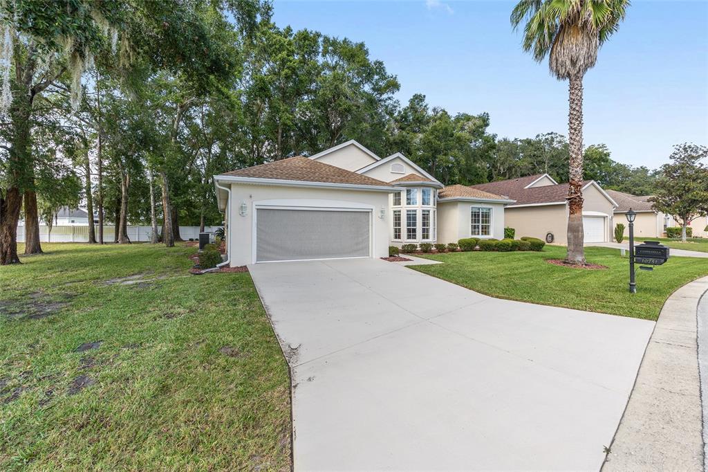 10751 Southwest 71st Circle Ocala, FL 34476 - Photo 22 of 52 a front view of a house with a yard and palm trees