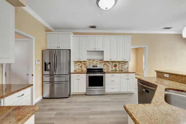 a kitchen with granite countertop a refrigerator stove top oven and sink