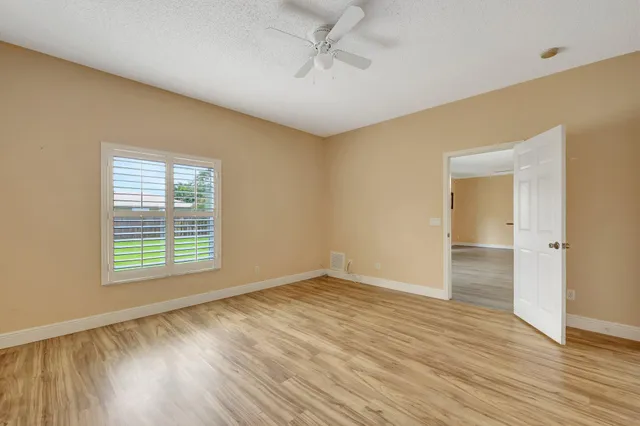 an empty room with wooden floor cabinet and windows