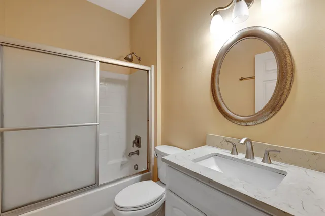 a bathroom with a granite countertop sink toilet and a mirror