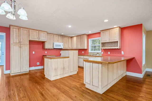 a kitchen with kitchen island granite countertop wooden floors and a sink
