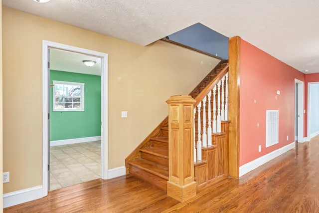 a view of a hallway with wooden floor and staircase