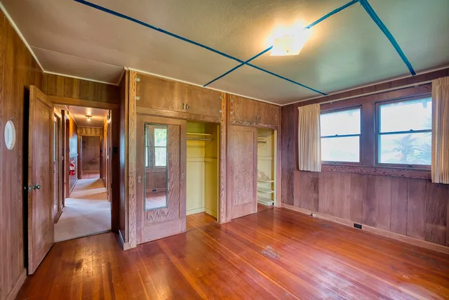 a view of empty room with wooden floor and fan