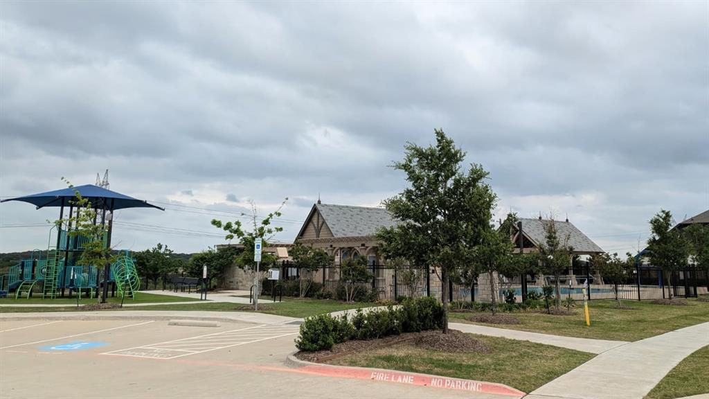 1140 Knightsbridge Road Argyle, TX 76226 - Photo 12 of 13 Community amenities include a playground with a blue shade structure, a paved parking area, and a building with an ornate roof design
