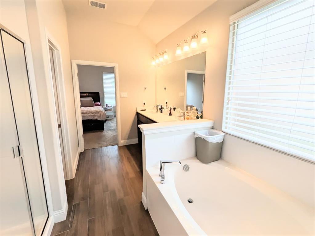 1140 Knightsbridge Road Argyle, TX 76226 - Photo 7 of 13 The bathroom features a built-in bathtub, a window with blinds, and a vanity with dual sinks and a mirror