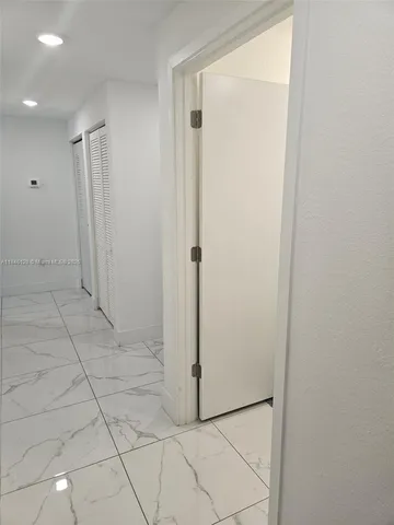 a view of a refrigerator in kitchen and an empty room in room