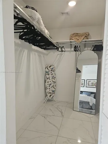 a view of walk in closet with clothes and shoes