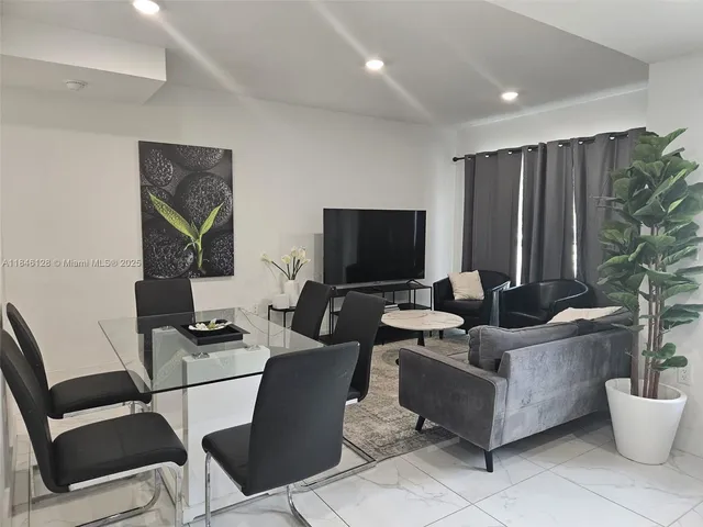 a living room with furniture a flat screen tv and a potted plant