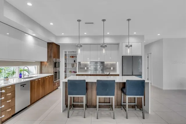 a kitchen with stainless steel appliances kitchen island granite countertop a refrigerator and a sink