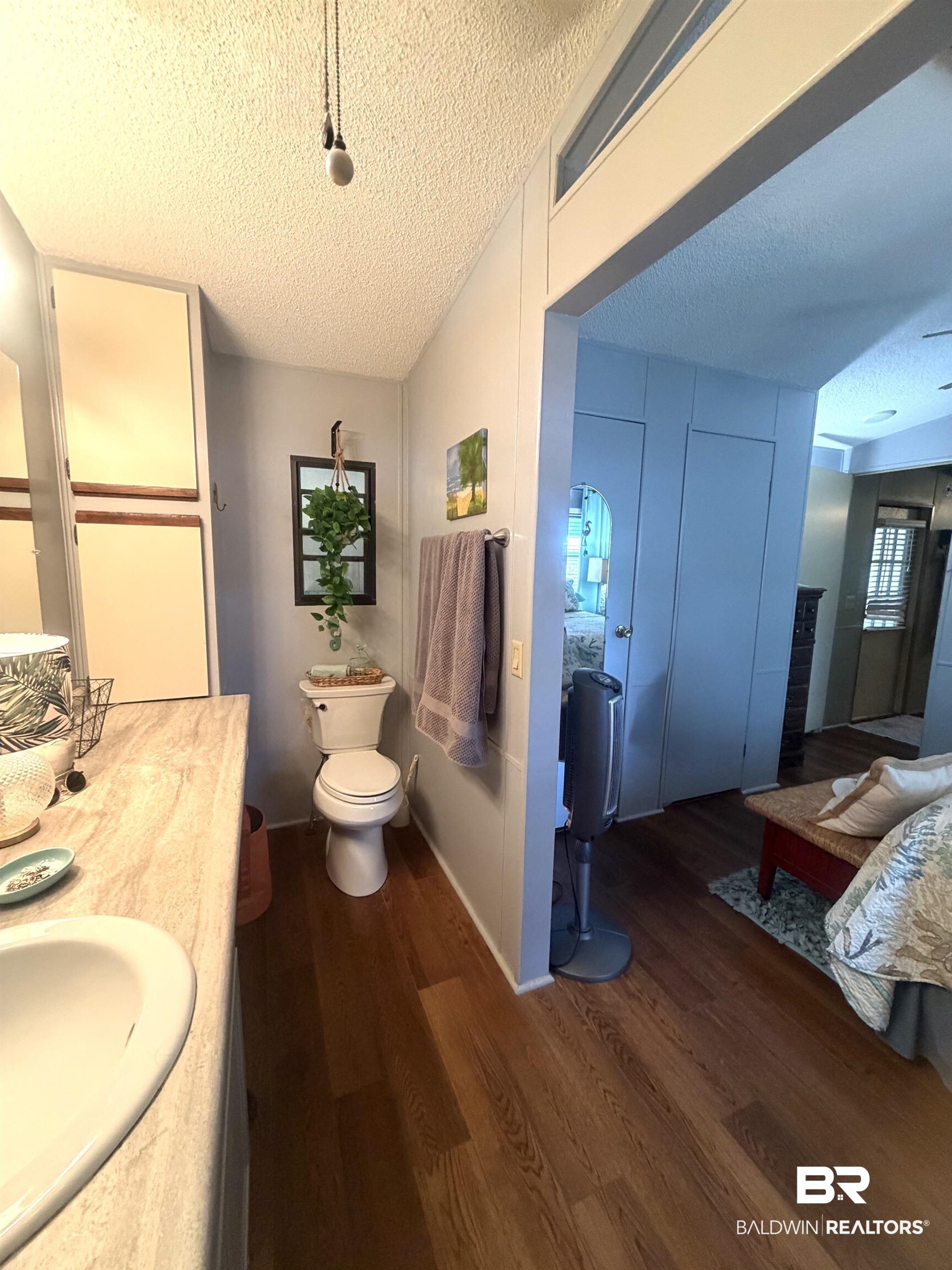 1620 Del Rey Drive Lillian, AL 36549 - Photo 17 of 45 Bathroom featuring wood-finish flooring, a single vanity with an integrated sink, built-in cabinetry, and a toilet