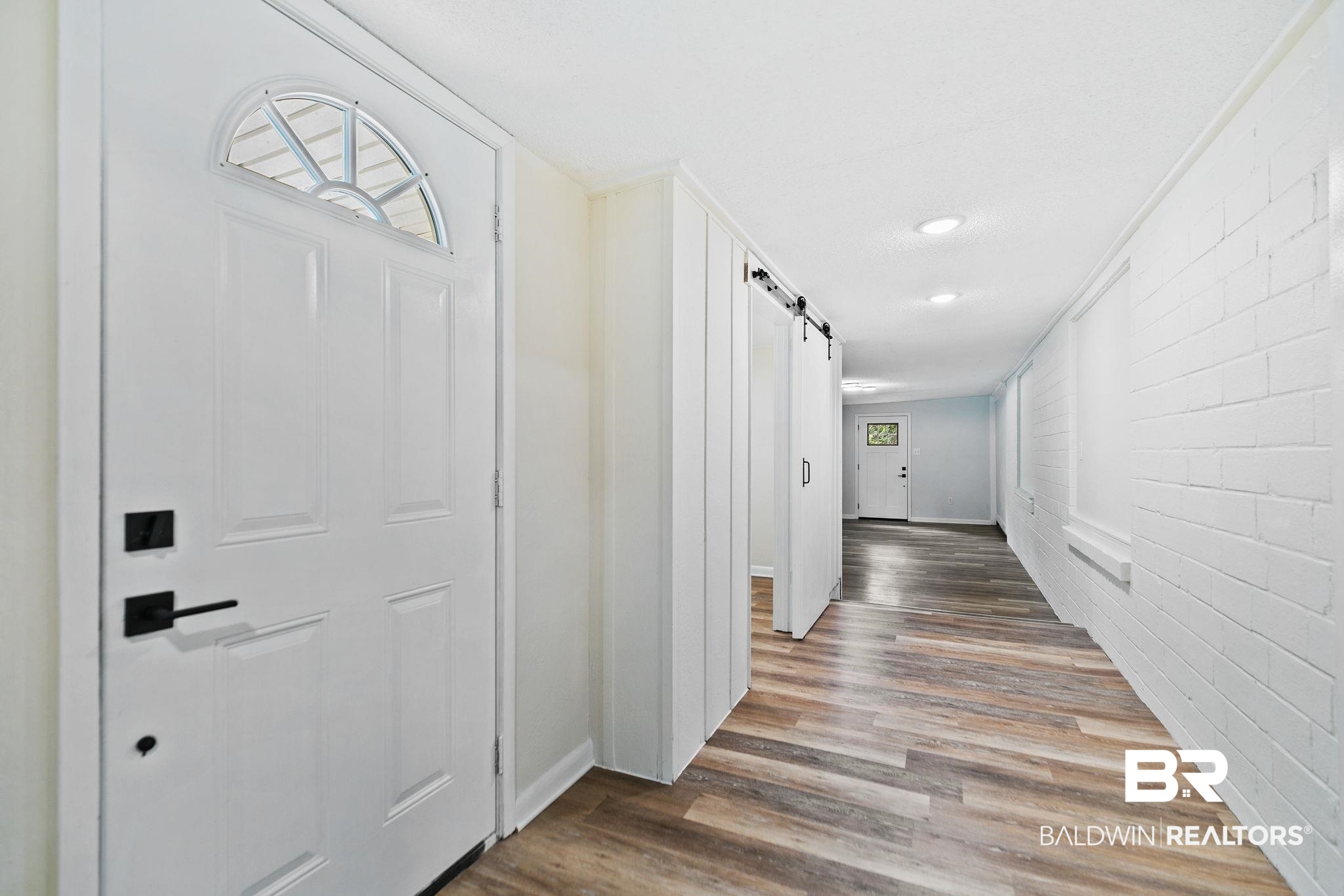 507 Byrne Street Bay Minette, AL 36507 - Photo 33 of 40 Hallway with brick wall, ornamental molding, a barn door, and wood-type flooring
