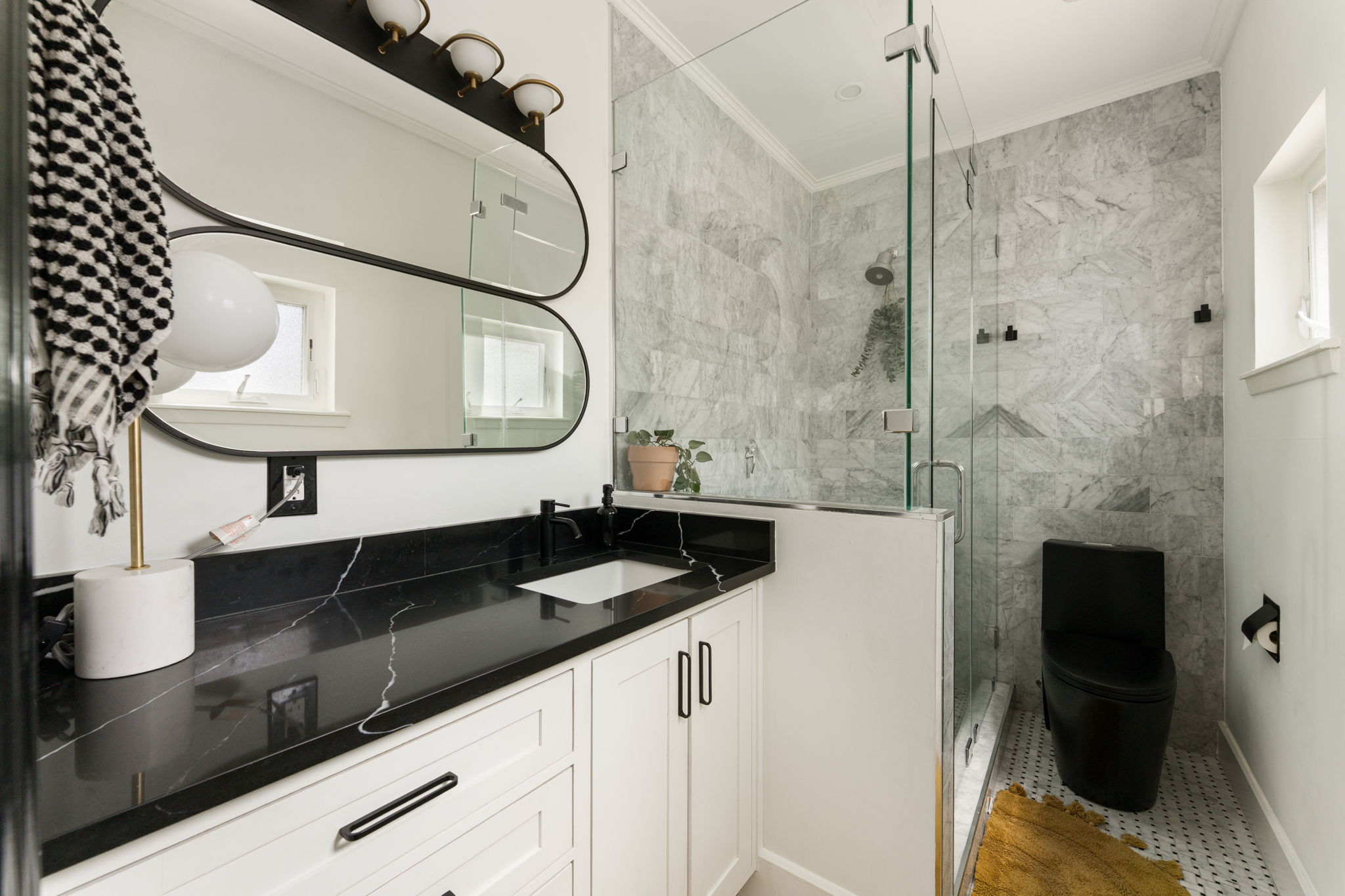 1704 Wethersfield Road Austin, TX 78703 - Photo 19 of 31 Contemporary bathroom featuring a spacious glass-enclosed shower, a vanity with a black countertop and white cabinetry, and a window providing natural light