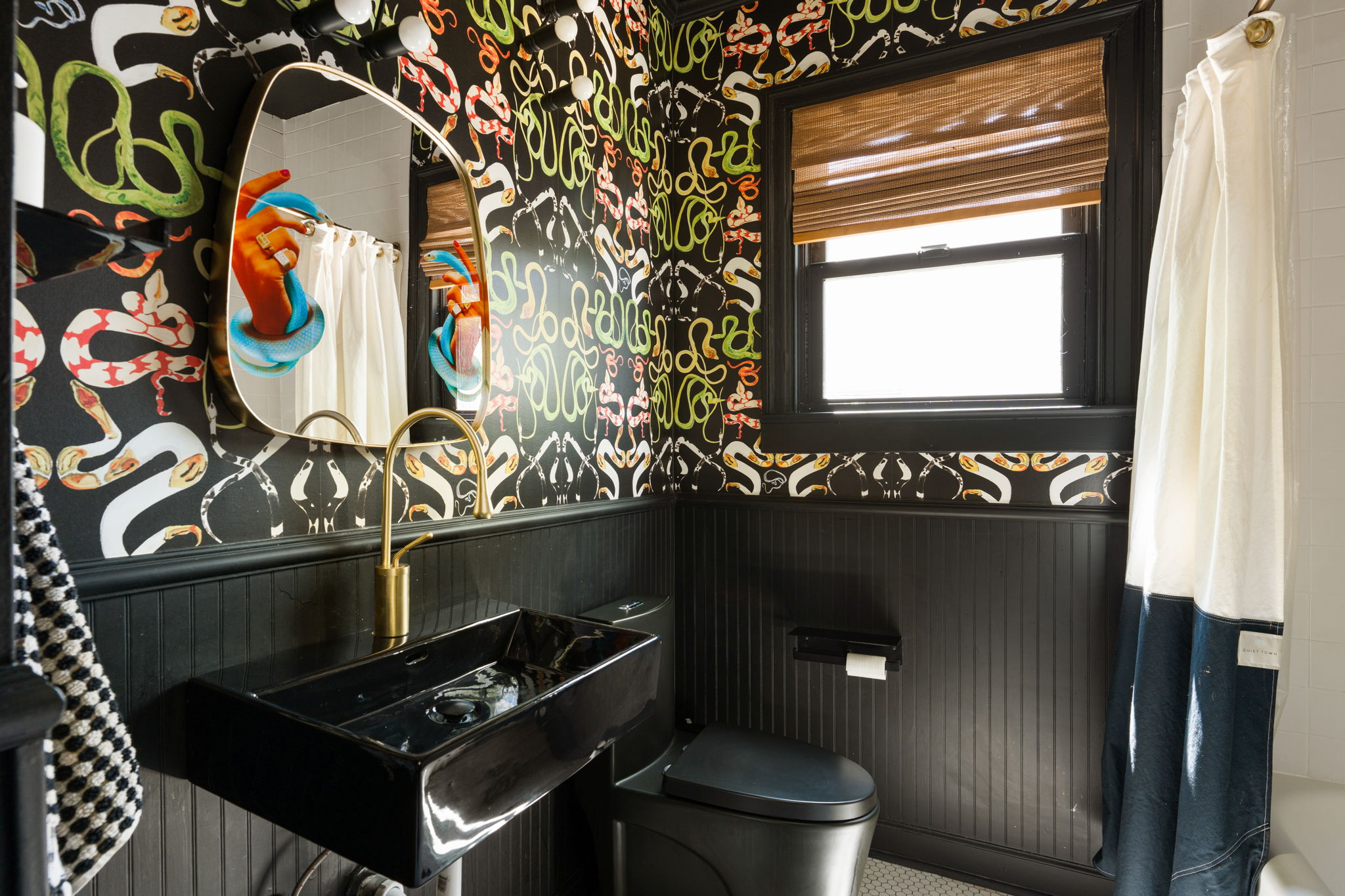 1704 Wethersfield Road Austin, TX 78703 - Photo 21 of 31 The bathroom features a unique design with patterned wallpaper, a black pedestal sink with a gold-toned faucet, and a contemporary wall mirror