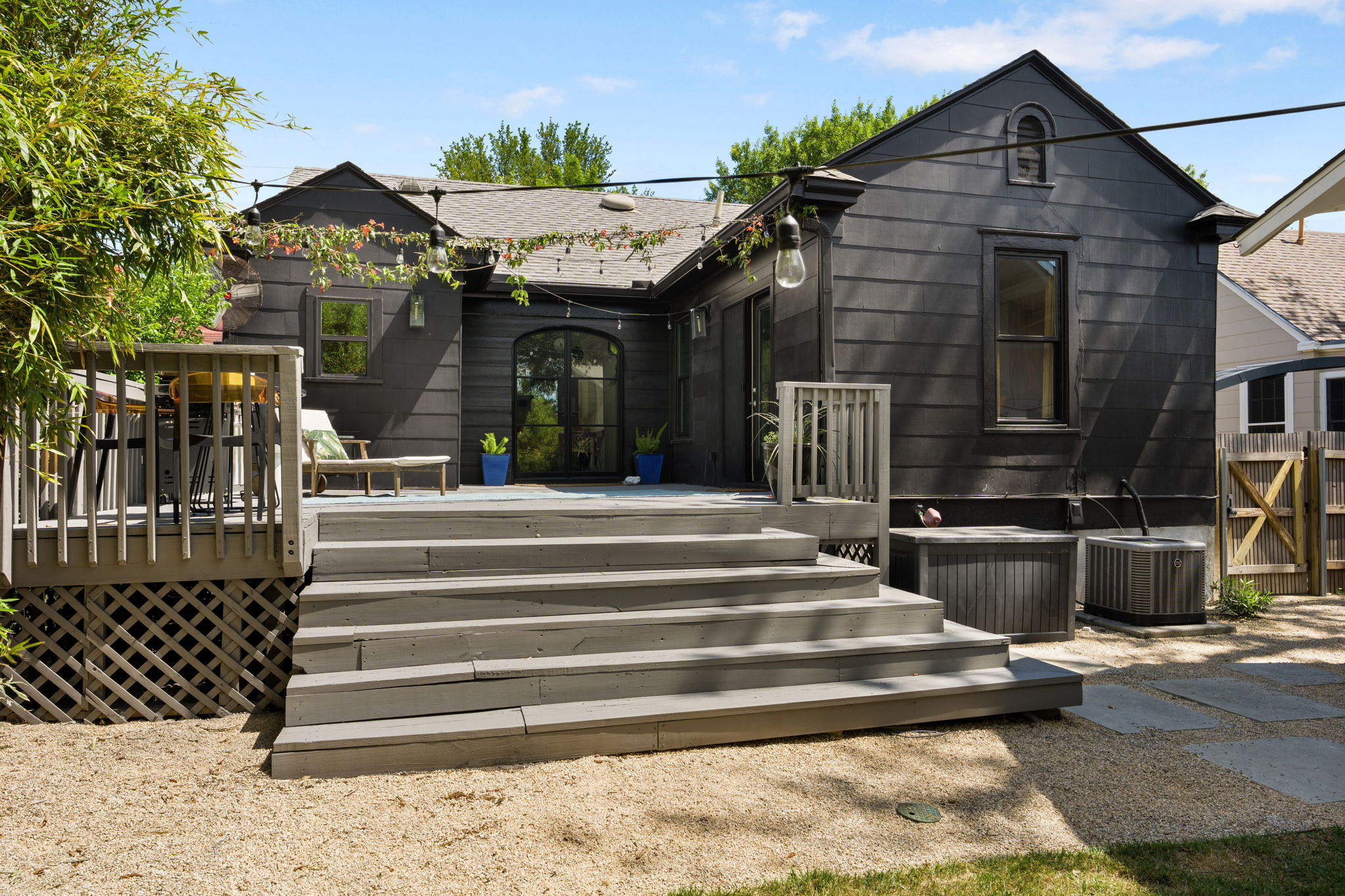 1704 Wethersfield Road Austin, TX 78703 - Photo 22 of 31 The property features a dark-colored exterior with a wooden deck and steps leading down to a gravel area