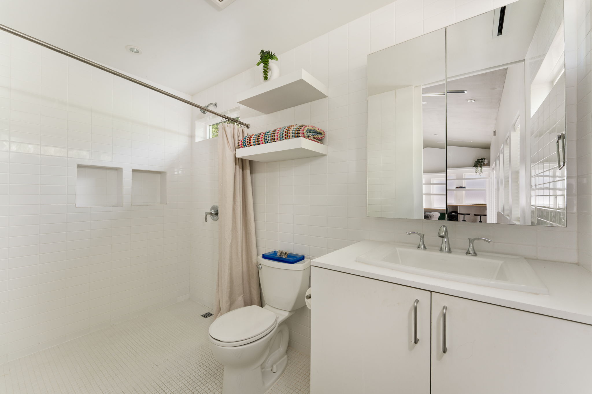 1704 Wethersfield Road Austin, TX 78703 - Photo 29 of 31 The bathroom features an integrated shower area with white subway tile, a toilet, and a vanity with a white countertop and cabinet storage