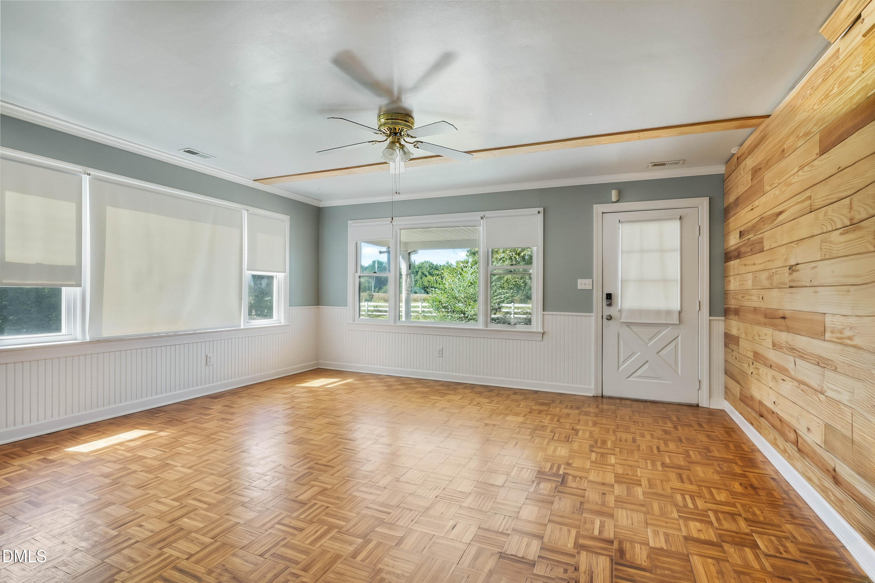 7406 Old Beulah Road Kenly, NC 27542 - Photo 4 of 30 Parquet wood flooring, a decorative wood accent wall, multiple windows, beadboard wainscoting, and a ceiling fan
