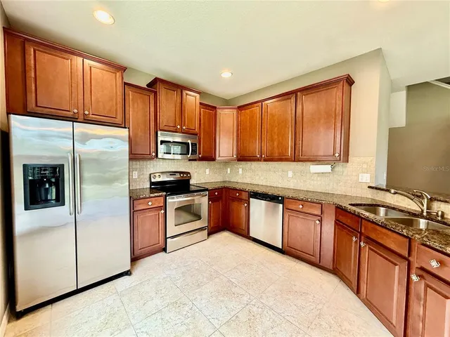a kitchen with stainless steel appliances granite countertop a refrigerator stove top oven a sink and dishwasher