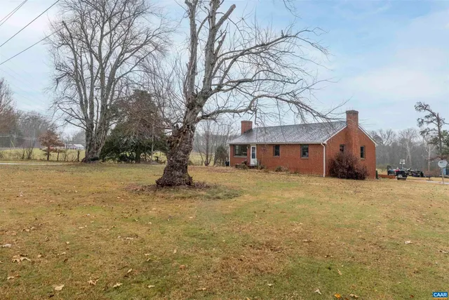 a view of house with yard and trees in the background