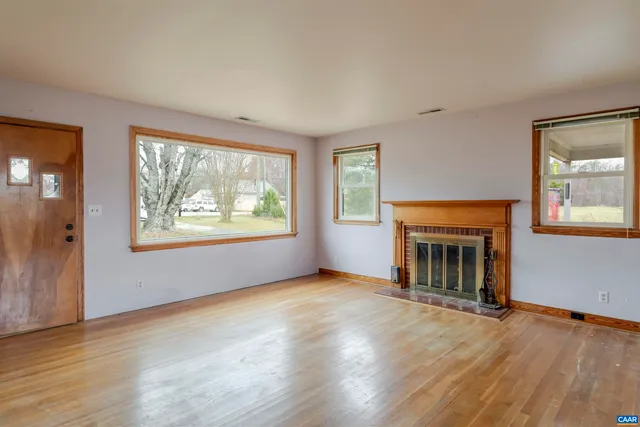 an empty room with windows fireplace and wooden floor
