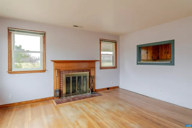 an empty room with windows and fireplace