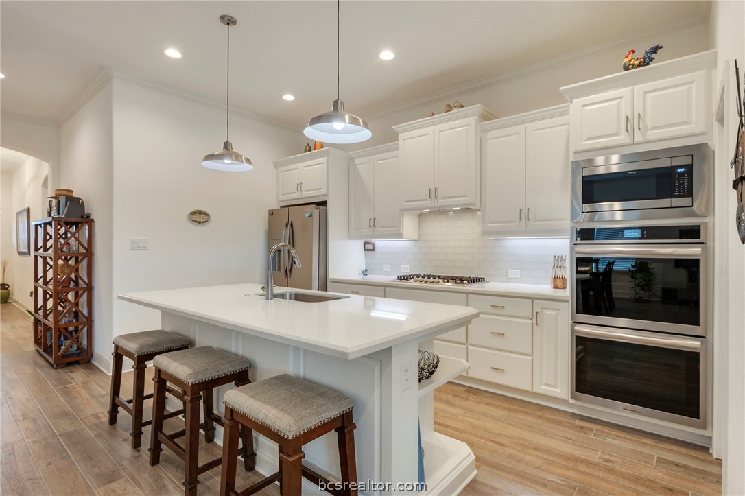 3500 Abingdon Cove Bryan, TX 77808 - Photo 2 of 23 a kitchen with stainless steel appliances kitchen island granite countertop a stove a sink a oven a dining table and chairs with wooden floor
